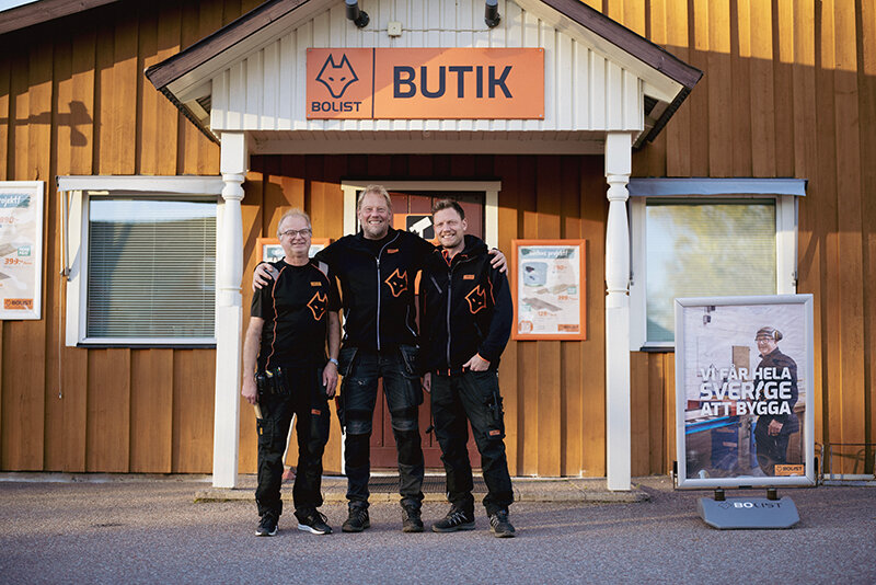 Tre personer i BOLIST-kläder framför butiksentrén